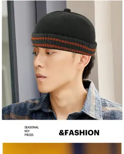 Close-up of a stylish black knitted docker hat with orange stripes on a male model.