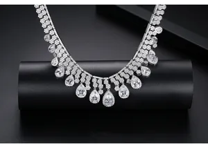 Vista detallada de collar de flecos plateado con circonitas brillantes en pera.