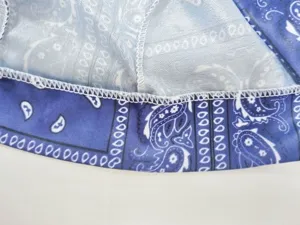 Dettaglio ravvicinato della cucitura overlock bianca su tessuto bandana blu con paisley