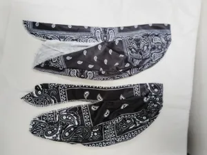 Dettaglio ravvicinato di foulard elastico nero con motivo paisley bianco e trama setosa.