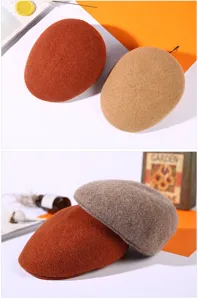 Detailed macro view of warm wool beret hats in autumnal colors like orange and beige.