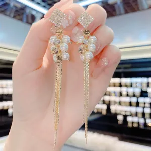 Élégantes boucles d'oreilles dorées à glands avec carrés sertis de diamants et perles.