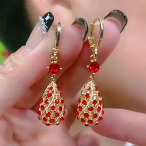 Macro view of French vintage gold dangle earrings with red rhinestones