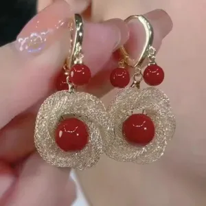 Close-up view of vintage French style red pearl earrings with exquisite gold woven mesh