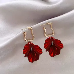 Close-up of elegant French style earrings with deep red petal pendants