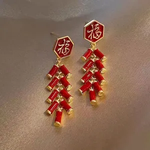 Detailed view of red firecracker tassel earrings with festive Fu character design.