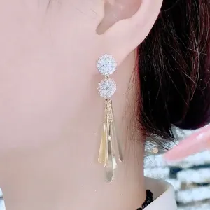 Side detail of elegant rhinestone floral wing tassel earrings worn by a model