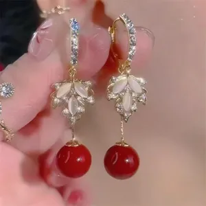Close-up of French retro leaf earrings with elegant red beads and opal-like stones