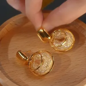 Primer plano de pendientes geométricos dorados con malla y piedras brillantes en madera