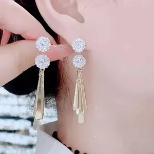 Close-up of sparkling flower-shaped cluster earrings with long gold tassel fringe
