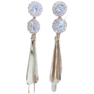 Detailed macro view of sparkling rhinestone flower and long metallic wing tassel earrings