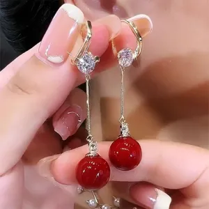 Close-up of elegant French vintage earrings with long gold tassels and red beads