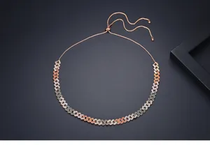 Détail d'un collier chaîne gourmette réglable en or rose avec zircons colorés pavés.