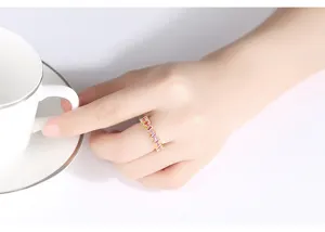 Primer plano detallado de un anillo de oro con circonitas rosas y rojas en la mano con taza