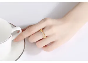Primer plano de un elegante anillo de oro con gemas de colores del arco iris en la mano