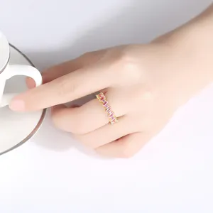 Elegante anillo de latón dorado con circonitas rectangulares rosas usado en la mano