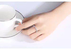 Close-up van een elegante verzilverde koperen ring met zirkonia op een vrouwenhand.