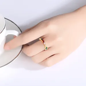 Anillo geométrico de oro con circonitas de colores usado en una mano femenina elegante