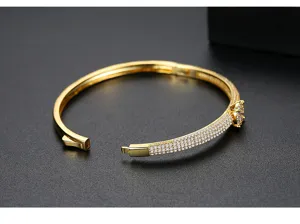 Detalle de un brazalete dorado con circonitas micro-pave y diseño de racimo lateral