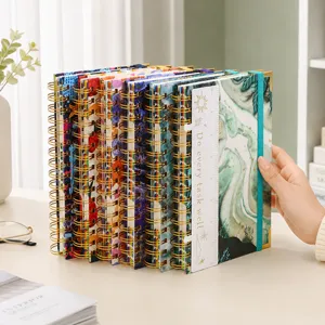 Detailansicht von A5-Spiralnotizbüchern mit bunten Einbänden und goldenen Metallspiralen