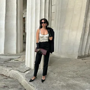 Detailed view of a white polka dot camisole worn with chic black gloves and clutch bag