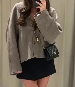 Detalle de una chaqueta corta de lana con cuello en V en color café de estilo urbano.
