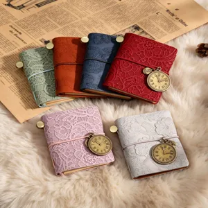 Mini carnet de voyage vintage avec couverture en dentelle gaufrée et pendentif horloge.
