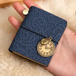 Mini carnet de voyage vintage avec couverture en dentelle et pendentif horloge rétro.