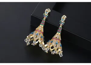 Détail macro de boucles d'oreilles style plumes de paon avec cristaux colorés et fini doré