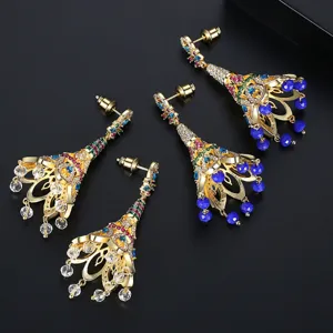 Elégantes boucles d'oreilles à pompons dorées avec zircons et perles bleues.