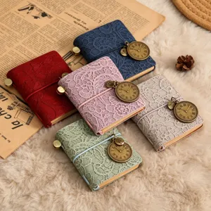 Mini carnet de voyage vintage avec couverture en dentelle, élastique et pendentif horloge.