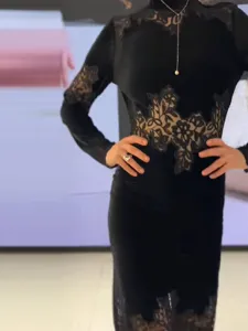 Detailopname van een zwarte fluwelen jurk met verfijnd kantwerk en een elegante hoge hals.