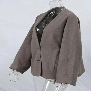 Vista lateral de una chaqueta corta de lana color topo con cuello en V en maniquí