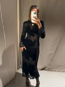 Elegante maxi-jurk van zwart fluweel met delicaat kant-patchwork en lange mouwen.