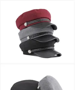 Close-up of stylish wool baker boy caps in red, grey, and black with leather brims.
