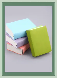 Stapel von vier bunten A6-Hardcover-Notizbüchern in Blau, Lila, Rosa und Grün auf Grau