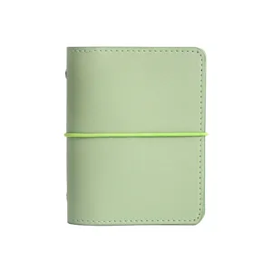 Pequeño cuaderno de cuero verde menta con cierre elástico y costuras blancas