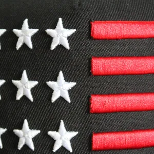 Détail macro des étoiles brodées et des rayures rouges sur une casquette hip-hop noire