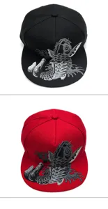 Detailansicht der grauen Koi-Stickerei auf roten und schwarzen flachen Snapback-Mützen