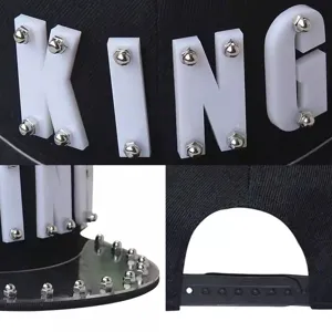 Dettagli di un cappellino hip-hop punk nero con lettere KING in acrilico e borchie argentate