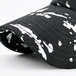 Close-up of a black baseball cap featuring a white graffiti ink splatter pattern