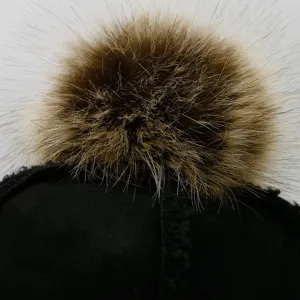 Close-up of a black suede baseball cap with a large fluffy brown fur pom-pom topper