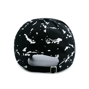 Back view of black baseball cap with white paint splatter print and adjustable strap