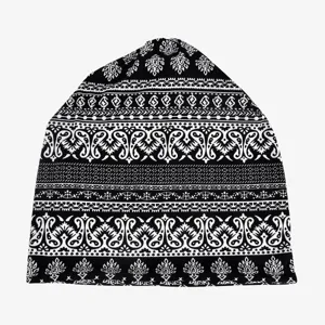 Detailed view of a black beanie with intricate white ethnic patterns and paisley motifs.