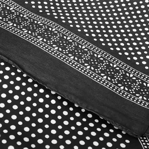 Detalle macro de una bandana negra con lunares blancos y borde de patrón floral detallado.