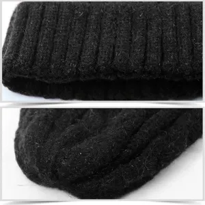 Primo piano di un berretto invernale nero in maglia a trecce con risvolto a coste morbido.