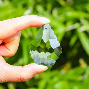 Macro view of a faceted K9 crystal suncatcher pendant held against a green background