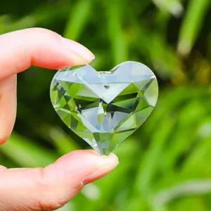 Detailed view of a faceted K9 clear heart crystal suncatcher held in hand outdoors