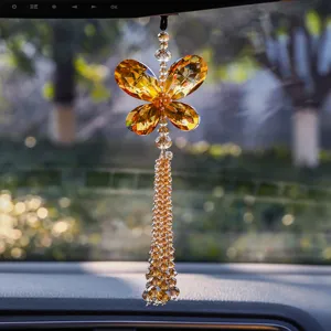 Close-up detail of luxurious amber crystal butterfly car pendant with beaded tassel