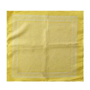 Primer plano de pañuelo cuadrado amarillo con lunares blancos y bordes florales